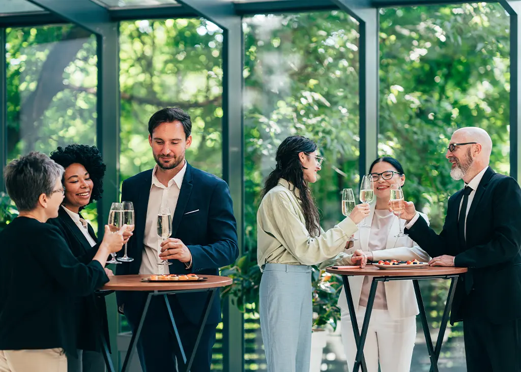 VIP guests enjoying champagne in a glass-walled hospitality suite at a major sports event.